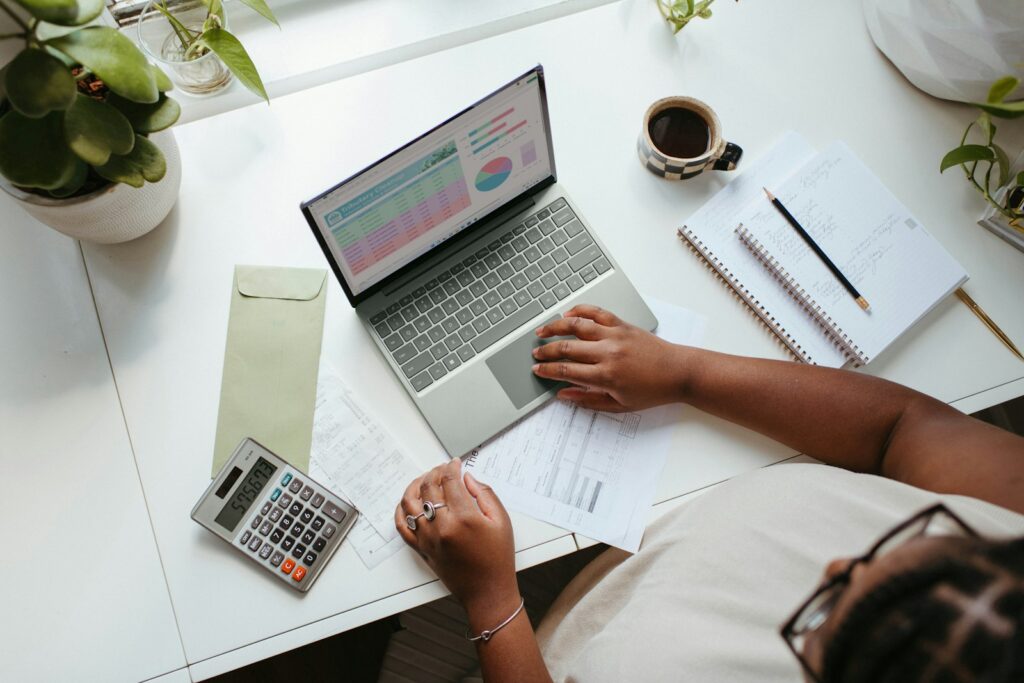 Business owner reviewing monthly management accounts with a laptop and calculator
